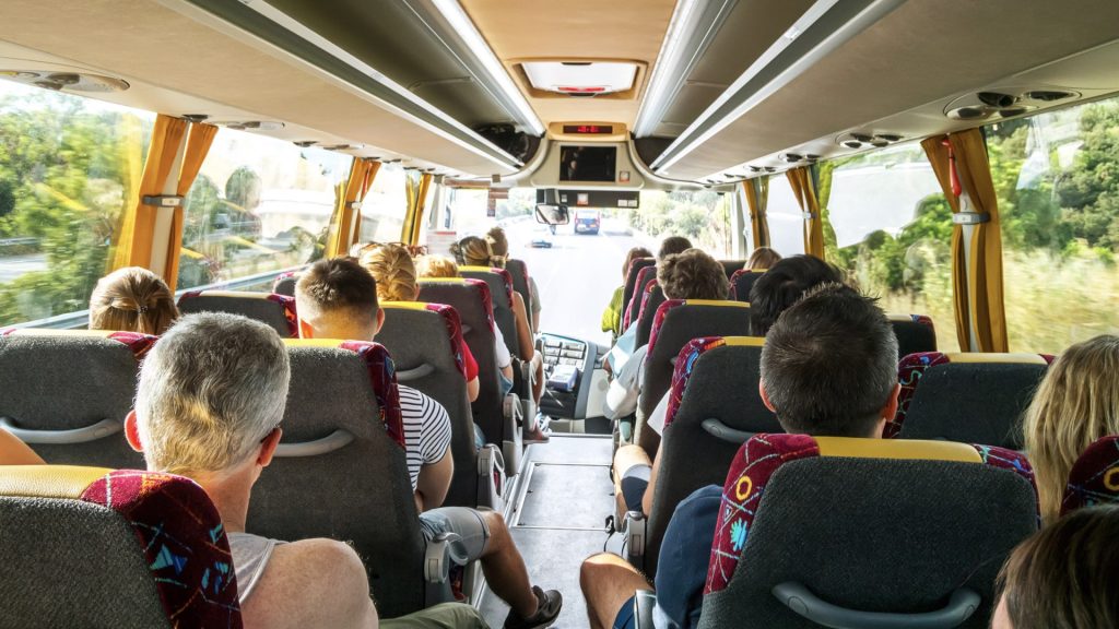People seated on a bus, all facing forward, symbolising getting the right people on board and moving together towards a shared business goal.